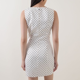 Model wearing Rotate Dress in Egret white with black polka dot print, sleeveless mini length, shown from back with zip detail.