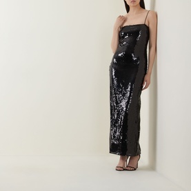 Model wearing Rotate black sequin maxi dress with spaghetti straps and sheer side panel, styled with black strappy heels