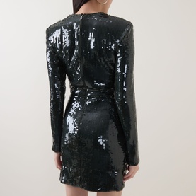 Model wearing Rotate Black Olive sequin mini dress, long sleeves, wrap-style waist, back view showing zip fastening.
