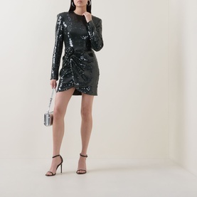 Model wearing Rotate Black Olive sequin mini dress with long sleeves and ruched detail, styled with silver box clutch and strappy heels