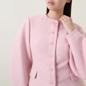 Model wearing Rotate Cherry Blossom jacket, collarless with pink button fastening and patch pockets, boucle-style fabric