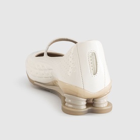 Off-white Mary Jane flat with textured upper, single ankle strap, and sculptural column heel, shown from rear three-quarter angle.