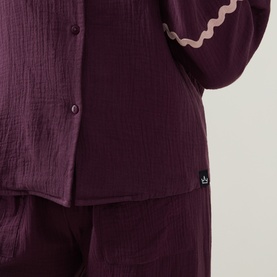 Model wearing Their Nibs Fig Baby Wavy-Trim Pyjama Set in fig, showing wavy trim detail at cuffs and button front on cotton top with matching