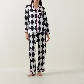 Model wearing Their Nibs cream and black harlequin diamond-print cotton pyjama set with pink trim collar and button-front top