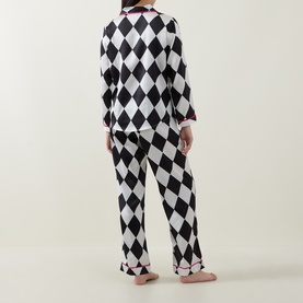 Model wearing Their Nibs cream and black diamond harlequin print cotton pyjamas, shown from the back, long sleeve top and full-length trousers.
