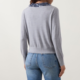 Model wearing Ulla Johnson Anna Embellished Cardigan in ash grey, back view, with blue sequin collar detail and light blue jeans.