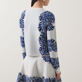 Model wearing Ulla Johnson Carina Jacquard Cardigan in Lapis, featuring blue floral jacquard pattern on ivory, long sleeves and straight hem.