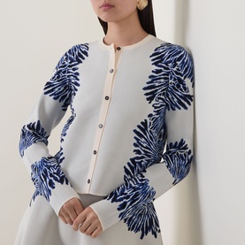 Model wearing Ulla Johnson Carina Jacquard Cardigan in Lapis, featuring blue floral jacquard pattern, round neck, gold button fastening, ribbed trims