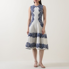 Model wearing Ulla Johnson dress in Lapis, sleeveless fit-and-flare silhouette with blue floral embroidery on ivory ground, styled with nude heeled