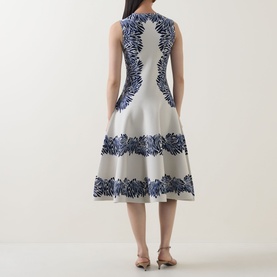Model wearing Ulla Johnson dress in Lapis, rear view, sleeveless fit-and-flare silhouette with navy floral jacquard panels on ivory ground.