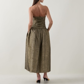 Model wearing Ulla Johnson Lumina Textured Gown in Light Gold, strapless midi dress with ruched bustier and flared skirt, styled with black heels