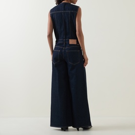 Model wearing Ulla Johnson Tigris denim jumpsuit, rear view, sleeveless with wide-leg silhouette in dark indigo cotton