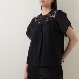 Model wearing Ulla Johnson Alma Embroidery Lace Silk Top in Noir, featuring floral lace yoke, short sleeves, and loose fit