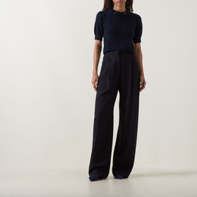 Model wearing Ulla Johnson Jude Embellished Top in Midnight, embellished round neck, short sleeves, styled with wide-leg navy trousers.