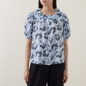 Model wearing Ulla Johnson Amaria Layered Stripe Top in Ciel, with ruffled collar, puffed short sleeves and floral graphic print.