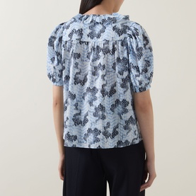 Model wearing Ulla Johnson Amaria Layered Stripe Top in Ciel, showing back view with puffed short sleeves and floral graphic print.