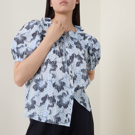 Model wearing Ulla Johnson Amaria Layered Stripe Top in Ciel, featuring puffed short sleeves, ruffled collar and abstract graphic print.