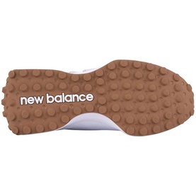 New Balance trainer sole view showing tan gum rubber outsole with chunky lug pattern and white New Balance logo text