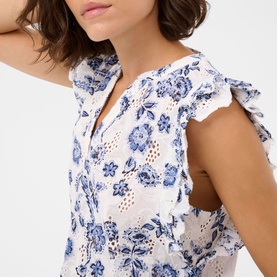 Model wearing Kaffe dress in Chalk Midnight Flower, white with blue floral print, broderie anglaise detail, flutter sleeves and V-neckline.