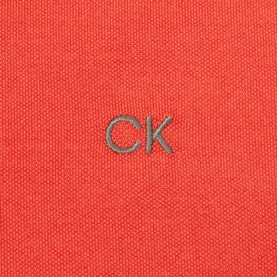 Calvin Klein Golf coral polo shirt close-up showing embroidered CK logo on piqu&eacute; fabric
