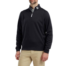 Model wearing black FootJoy quarter-zip pullover with white zip placket and logo, styled with beige trousers