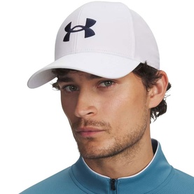 Model wearing Under Armour golf cap in white with navy logo, structured curved brim, worn with blue zip-neck top