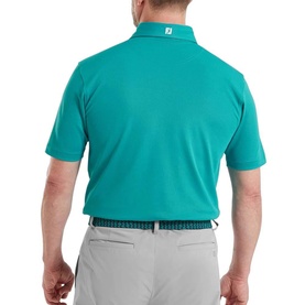 Model wearing FootJoy Tile Blue short-sleeve polo shirt, rear view, styled with light grey trousers and patterned belt.