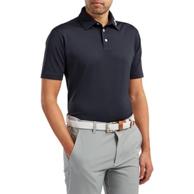 Model wearing Footjoy navy polo shirt with short sleeves and button placket, styled with grey trousers and a brown belt