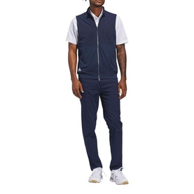 Model wearing Adidas Golf Collegiate Navy gilet with white polo shirt and navy trousers, styled with white trainers