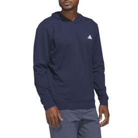 Model wearing Adidas Golf hoodie in Collegiate Navy with small white logo on chest, paired with grey trousers.