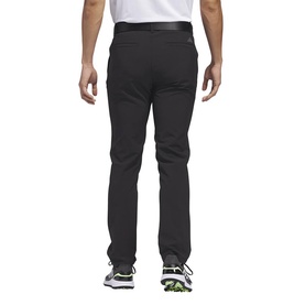 Model wearing Adidas Golf black trousers, rear view, styled with white trainers. Slim fit with clean back pockets.