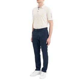 Model wearing Calvin Klein Golf navy trousers, styled with a cream polo shirt and white trainers.