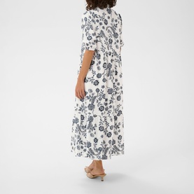 Model wearing Kaffe dress in Chalk Midnight Flower, back view, white with navy floral print, midi length, short sleeves, styled with nude heeled