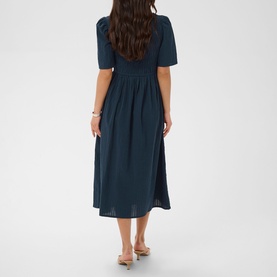 Model wearing Kaffe Midnight Marine midi dress with short sleeves and gathered waist, shown from behind, styled with nude heeled sandals