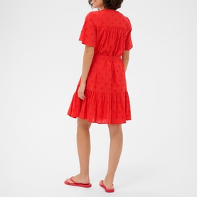 Model wearing Kaffe Poppy Red short sleeve mini dress with tiered skirt and broderie fabric, styled with red flat sandals