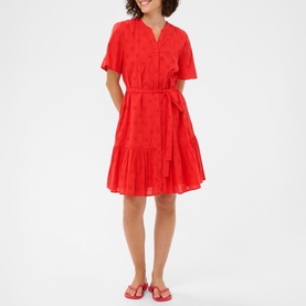 Model wearing Kaffe Poppy Red short-sleeve belted tiered mini dress with broderie fabric, styled with red flat sandals.