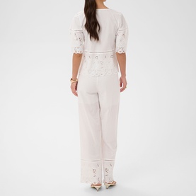 Model wearing Kaffe chalk white lace-trim jumpsuit with broderie anglaise detail, elbow-length sleeves and wide-leg trousers, back view