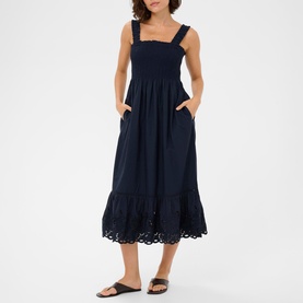 Model wearing Kaffe midi dress in Midnight Marine, featuring smocked bodice, eyelet hem frill, wide straps and side pockets, styled with black sandals