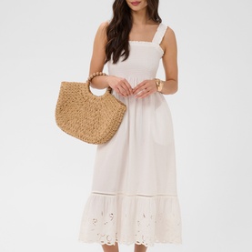 Model wearing Kaffe chalk midi dress with broderie anglaise hem trim, styled with a woven straw tote bag and gold bracelet.