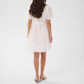 Model wearing Kaffe chalk white tiered mini dress with short puff sleeves and belted waist, styled with nude heeled mules
