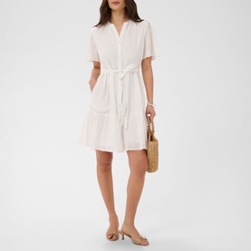 Model wearing Kaffe chalk white short-sleeve tiered shirt dress with tie waist, styled with nude sandals and woven bag