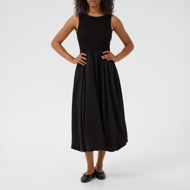 Model wearing Kaffe black deep sleeveless midi dress with fitted bodice and full gathered skirt, styled with black flat shoes