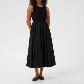 Model wearing Kaffe black deep sleeveless midi dress with fitted knit bodice and full woven skirt, styled with black flat shoes