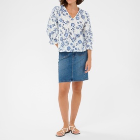 Model wearing Kaffe Chalk Midnight flower print blouse with blue floral pattern, styled with denim mini skirt and white sandals.