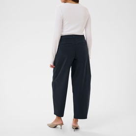 Model wearing Kaffe wide-leg trousers in Midnight Marine, cropped length, paired with a white long-sleeve top and silver heels, rear view.