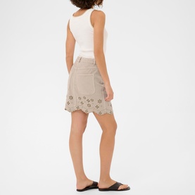 Model wearing Kaffe Feather Gray mini skirt with floral broderie anglaise hem, styled with white vest top and black slides