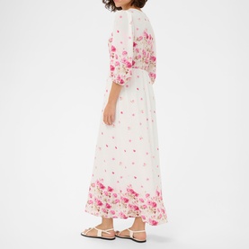 Model wearing Kaffe white rose border flower maxi dress with puff sleeves, elasticated waist, and pink floral hem print, styled with white sandals