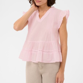 Model wearing Kaffe ballerina pink sleeveless top with ruffle cap sleeves, pintuck detail, and tiered hem, styled with beige trousers