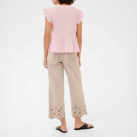 Model wearing Kaffe ballerina pink ruffle-sleeve top with beige wide-leg trousers featuring eyelet hem detail, styled with black flat sandals