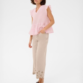 Model wearing Kaffe ballerina pink ruffle-sleeve peplum top with beige wide-leg cropped trousers featuring eyelet hem detail